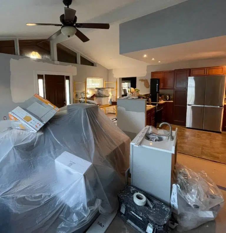 A chaotic living room during renovations, with a pile of furniture and tools in the center, illustrating renovation challenges